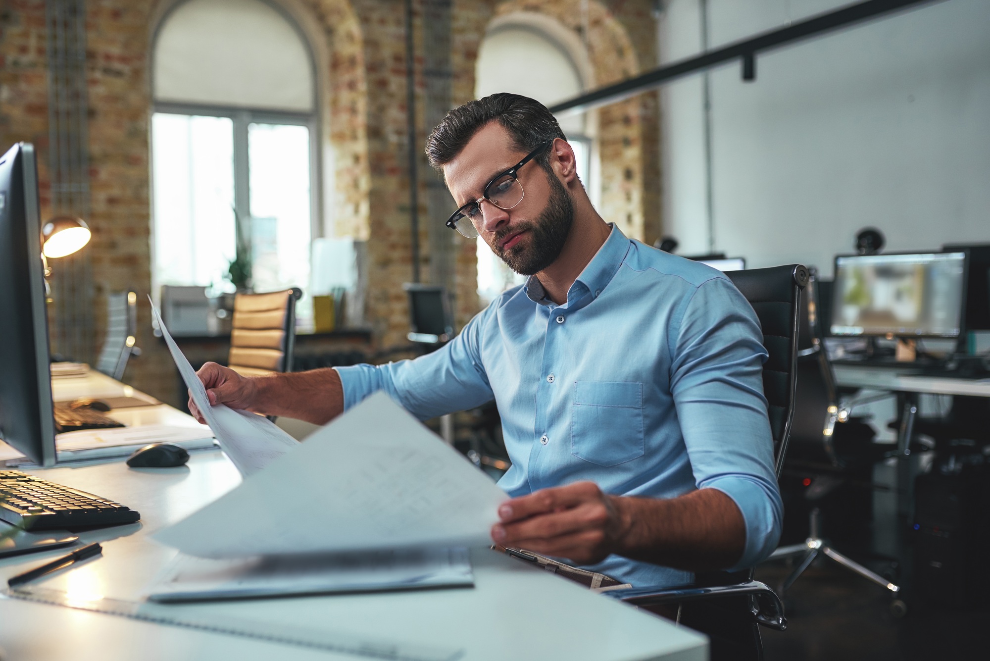 Construction concept. Concentrated bearded engineer in eyeglasses and formal wear looking at